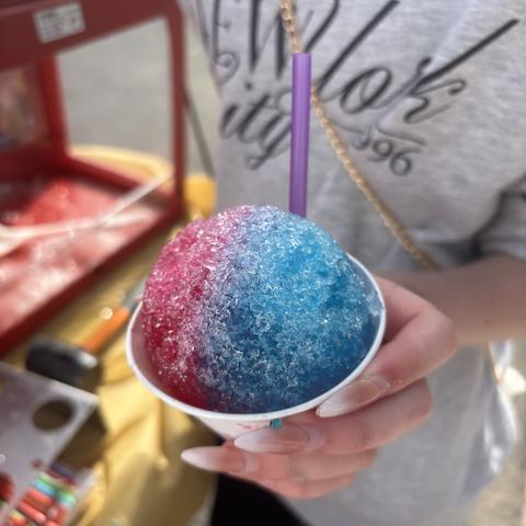 A red and blue snow cone in front of the snow cone machine